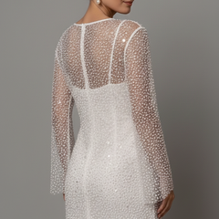 Female model wearing layered mini dress with long sleeves, back angle